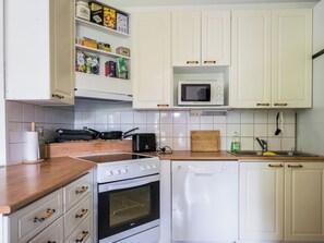 Una cocina con armarios blancos, un microondas, una estufa y un lavavajillas.