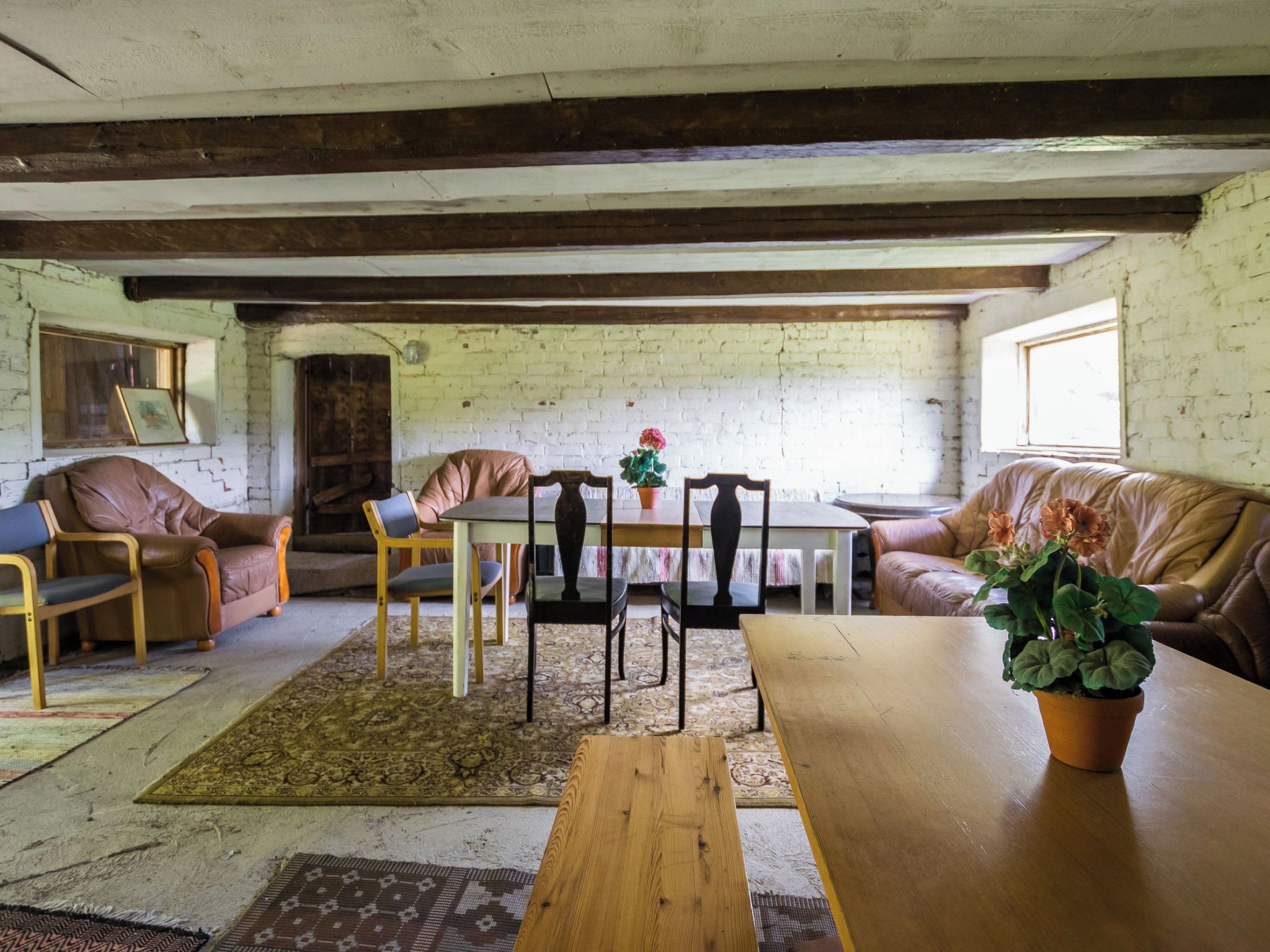 Een rustieke kamer met een houten tafel, lederen stoelen, een bank en een kamerbreed tapijt.