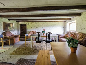 Una habitación rústica con una mesa de madera, sillas de cuero, un sofá y una alfombra estampada.
