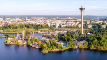 Vista aérea de una ciudad con una torre destacada, un río y un parque con atracciones.