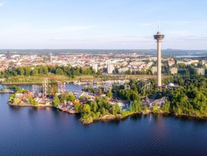 Ilmakuva kaupungista, jossa näkyy selkeästi korkea torni, joki ja huvipuistolaitteilla varustettu puisto.