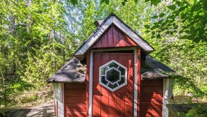 A red wooden structure with a hexagonal window, surrounded by trees. - Palttala by Interhome (Tampere)