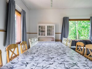 Comedor con una mesa larga, sillas, un aparador con puertas de vidrio y vista a zonas verdes.