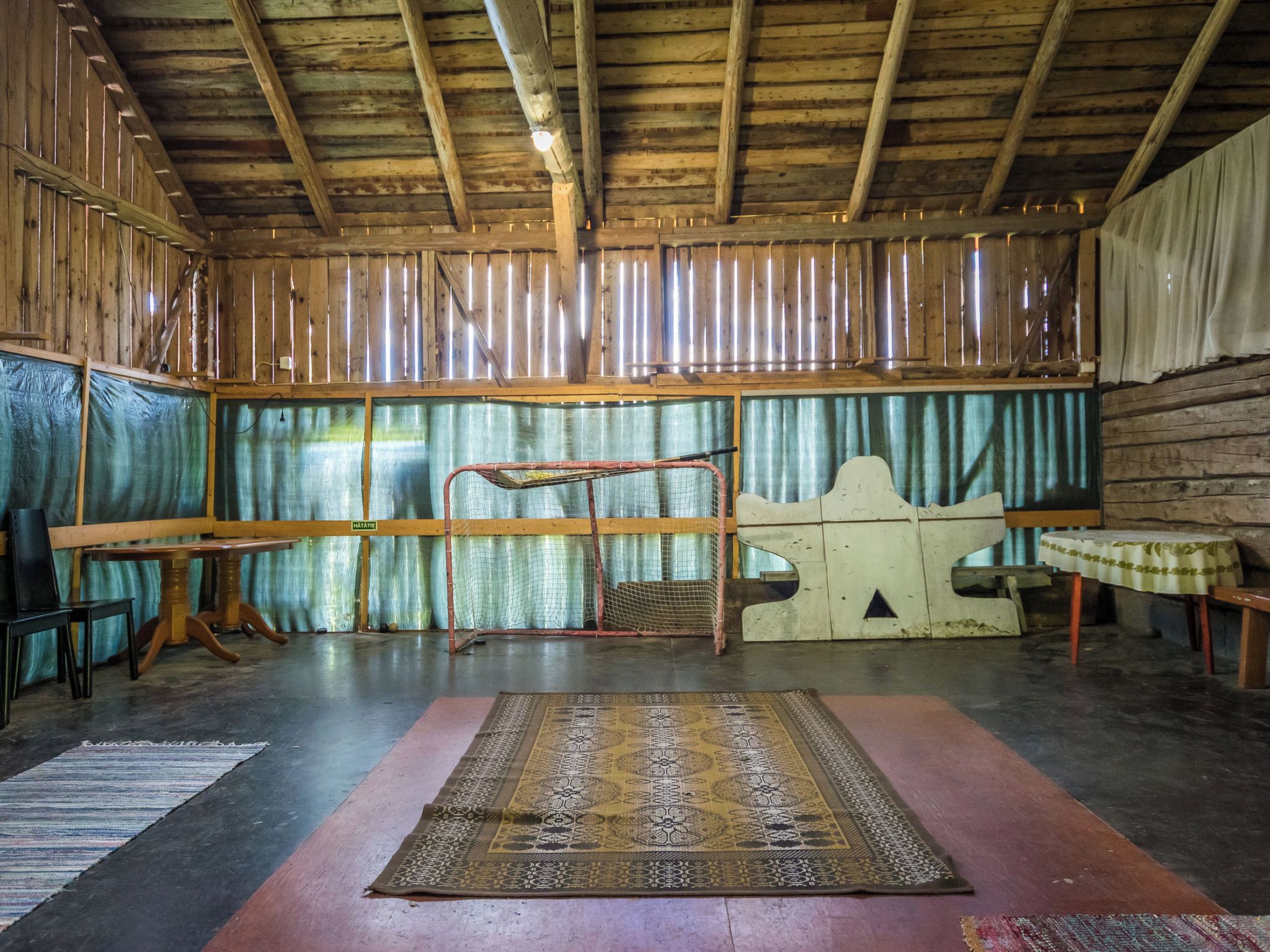 A rustic interior with wooden beams, a metal rack, a patterned rug, and a table.