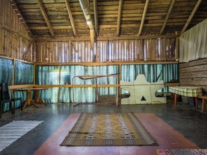 A rustic interior with wooden beams, a metal rack, a patterned rug, and a table.