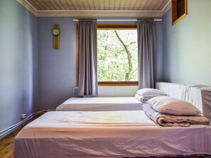 A room with two beds, a window with curtains, a wall clock, and a radiator. - Palttala by Interhome (Tampere)