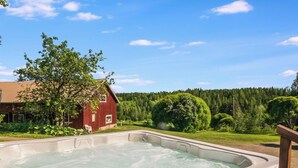 A hot tub outdoors with a red building and trees in the background. - Palttala by Interhome (Tampere)