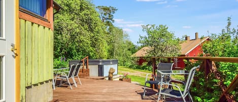 Une terrasse en bois avec des sièges d’extérieur et un jacuzzi.