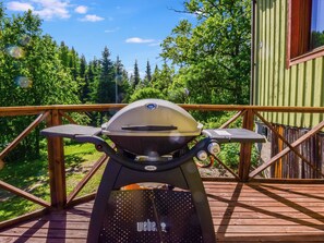 A Weber grill on an outdoor deck with a view of a forested area. - Palttala by Interhome (Tampere)