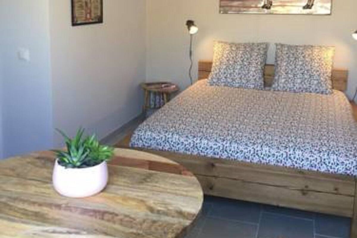 Ein Schlafzimmer mit einem Bett, einem Nachttisch mit Pflanze und einem Bild an der Wand.