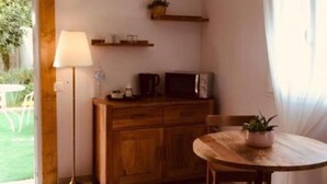 Eine Küche mit Holzschrank, Mikrowelle, Tisch mit Pflanze und Stehlampe.