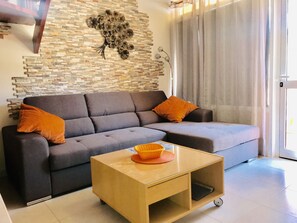 A modern living room with a grey sectional sofa, a small wooden coffee table, and a decorative wall piece.
