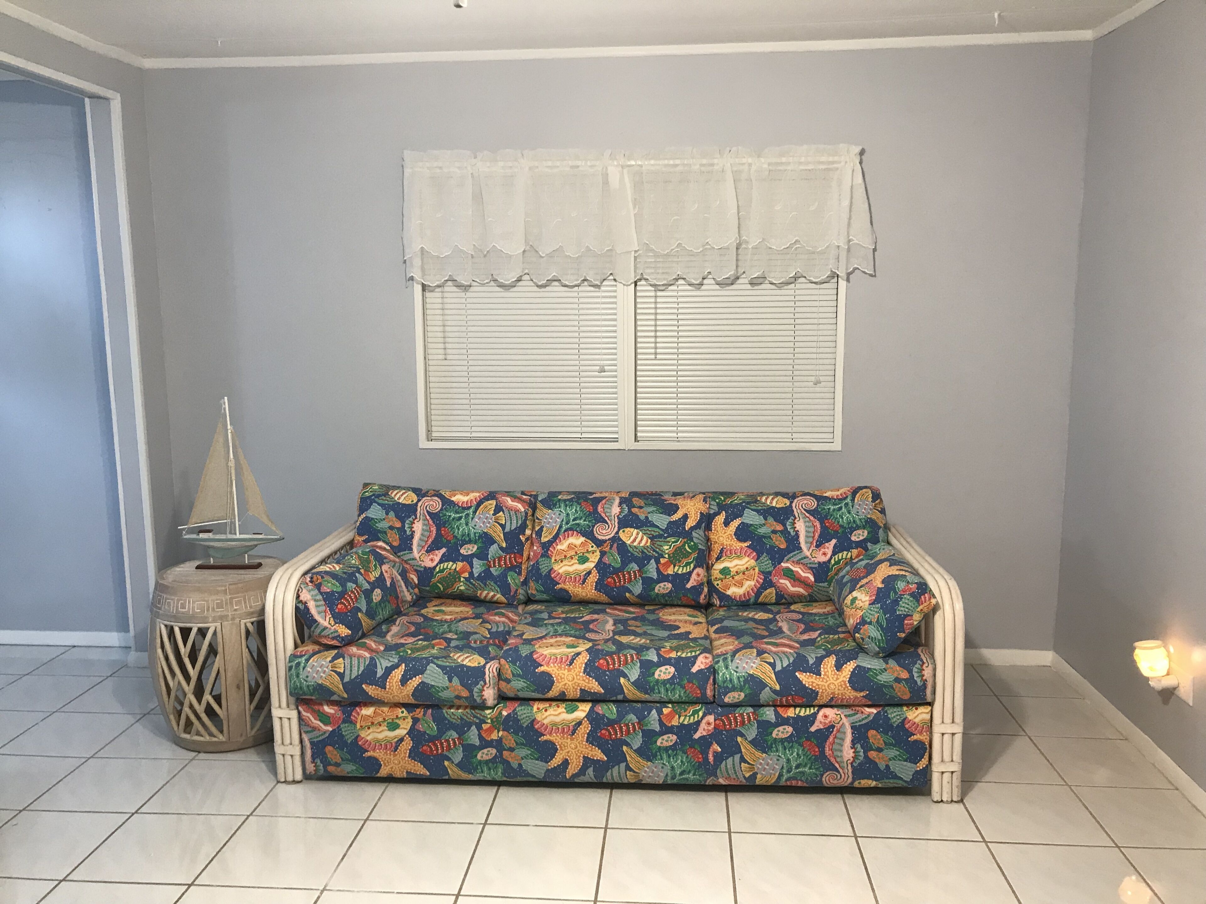 A room with a sofa, a window with blinds, a small round table, and a decorative item on the table.