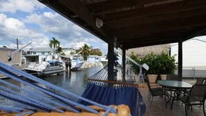 A hammock under a wooden roof, a table with chairs, and a view of boats and houses by the water. - Beautiful & Spacious Home with Dock Key Largo (Key Largo)