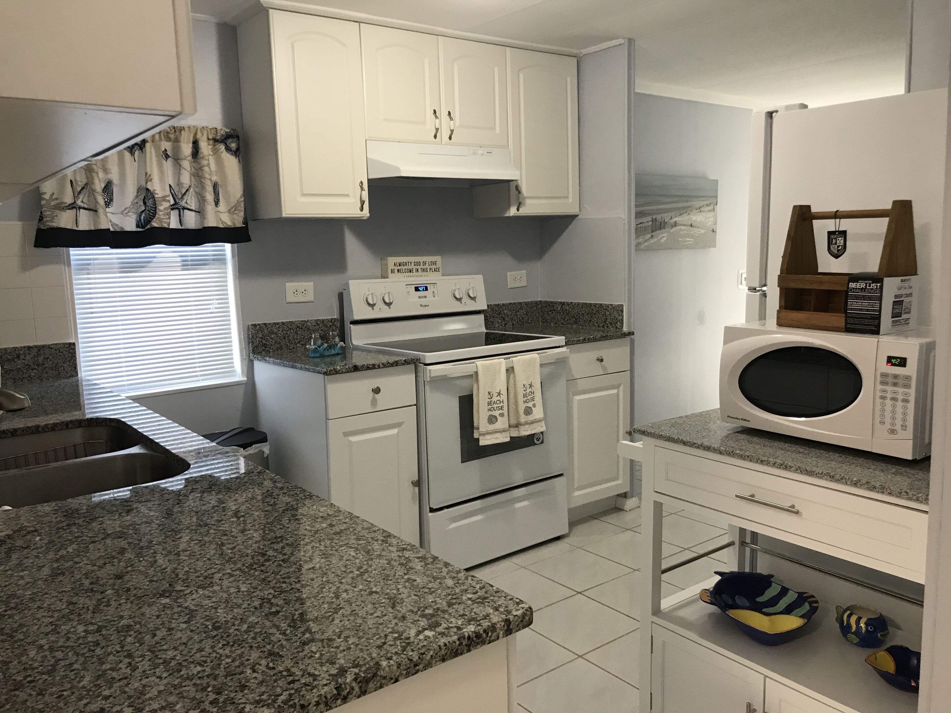 A kitchen with white cabinets, a built-in oven, a microwave, and a sink.