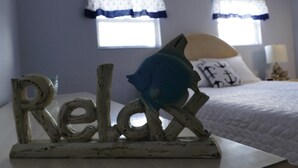 A bedroom with a bed, a decorative fish, and a 'Relax' sign. - Beautiful & Spacious Home with Dock Key Largo (Key Largo)