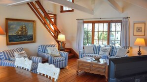 Ein gemütliches Wohnzimmer mit gestreiften Sofas, einem Holztisch und einer Treppe.