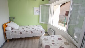 A room with two beds, a window, and a radiator. - Furnished house F3 on one level in Landes Chalosse in a gourmet region. (saint geours d auribat)