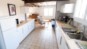 A kitchen with white cabinets, a wooden countertop, a chair, a table, and a window. - Furnished house F3 on one level in Landes Chalosse in a gourmet region. (saint geours d auribat)