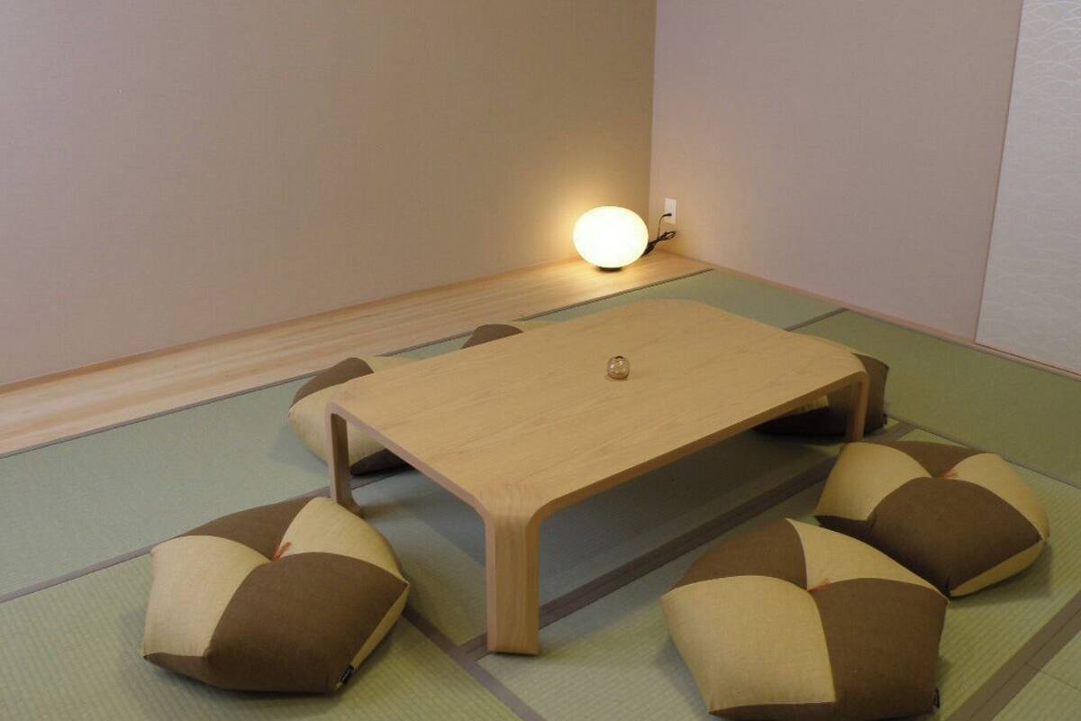 A room with tatami mat flooring, a wooden table, and cushions.