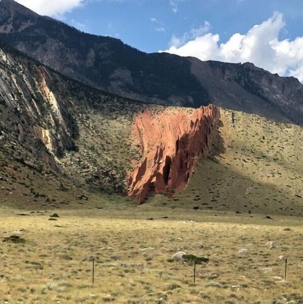 Un paisaje montañoso con una formación rocosa roja destacada.