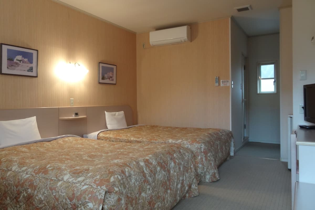 Een hotelkamer met twee bedden, een bureau en een televisie.