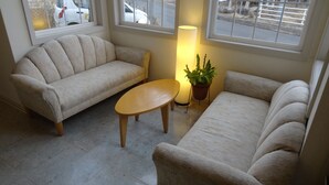 A living room with two beige sofas, a small wooden table, and a potted plant. - Family Lodge Hatagoya Nasu (Nasu)