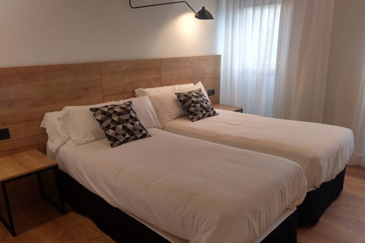 Ein Doppelbett mit Holz Kopfteil, zwei Nachttische und ein Kissen mit geometrischem Muster.
