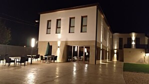 A modern building with a flat roof, large windows, and a covered outdoor seating area with tables and chairs. - Hotel Entrerailes (Casalarreina)