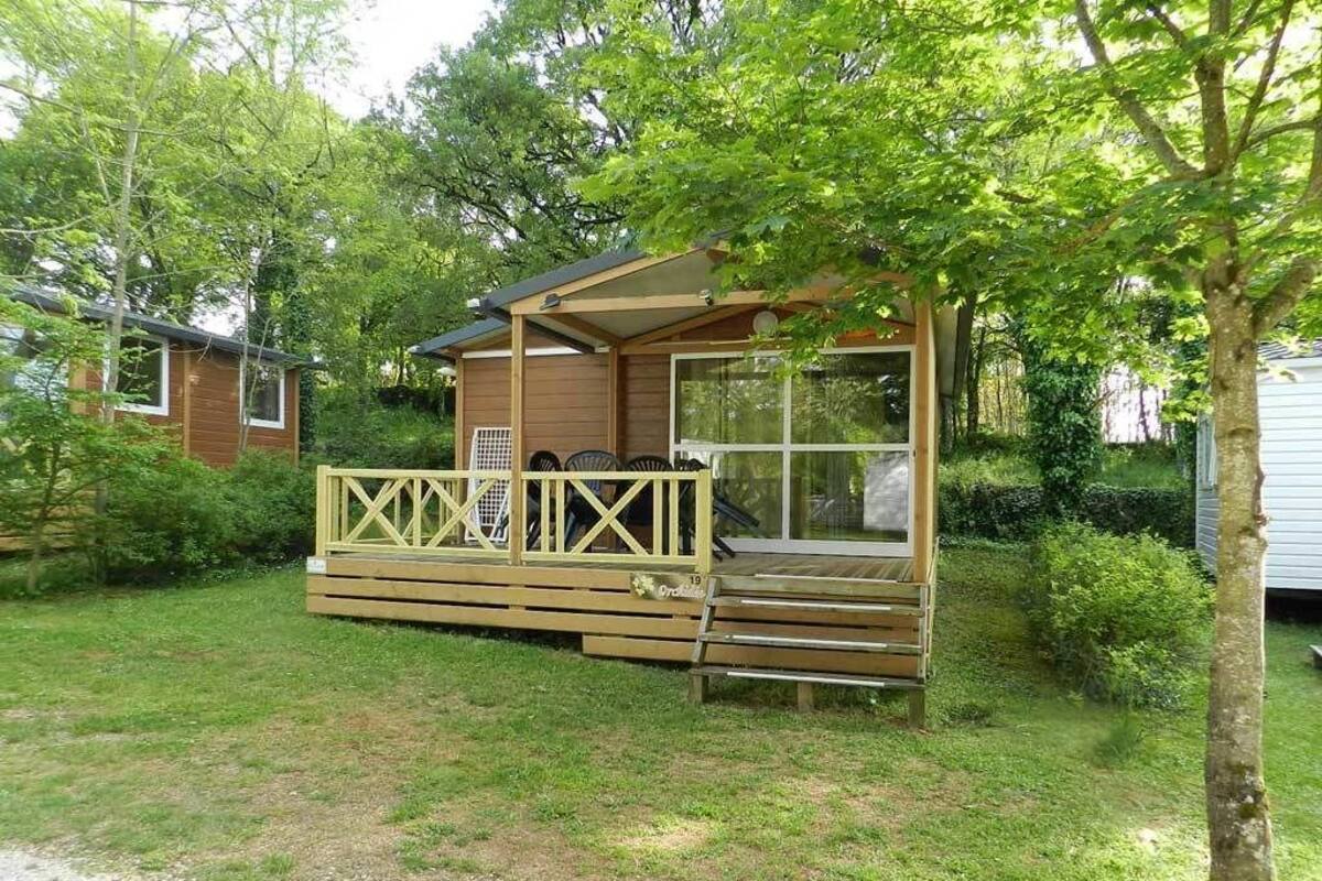 A wooden cabin with a deck, a covered porch, and a large window.