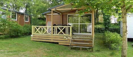 A wooden cabin with a deck, a covered porch, and a large window.