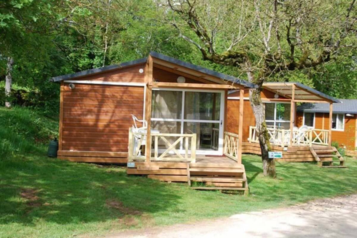 A wooden cabin with a porch and a glass door, surrounded by trees.