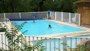 A swimming pool with a white fence, surrounded by greenery. - Camping Les Tilleuls - Chalets (Rocamadour)
