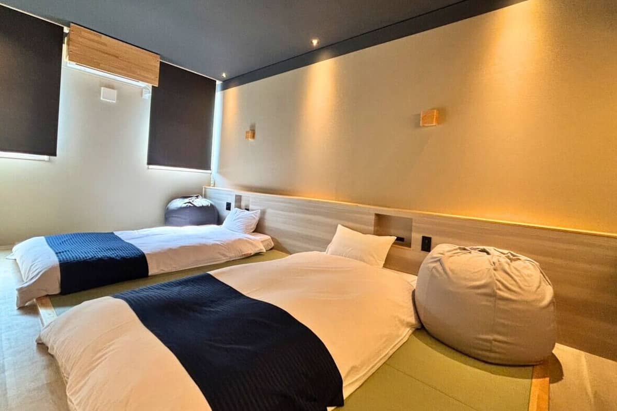 Ein Hotelzimmer mit zwei Betten, einem Sitzsack und einem Kopfteil mit integrierter Beleuchtung.