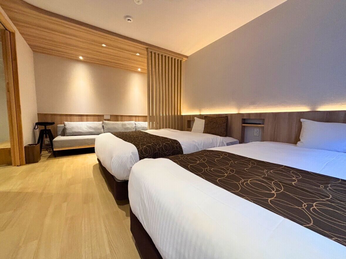 A hotel room with three beds, wooden paneling, and a modern design.