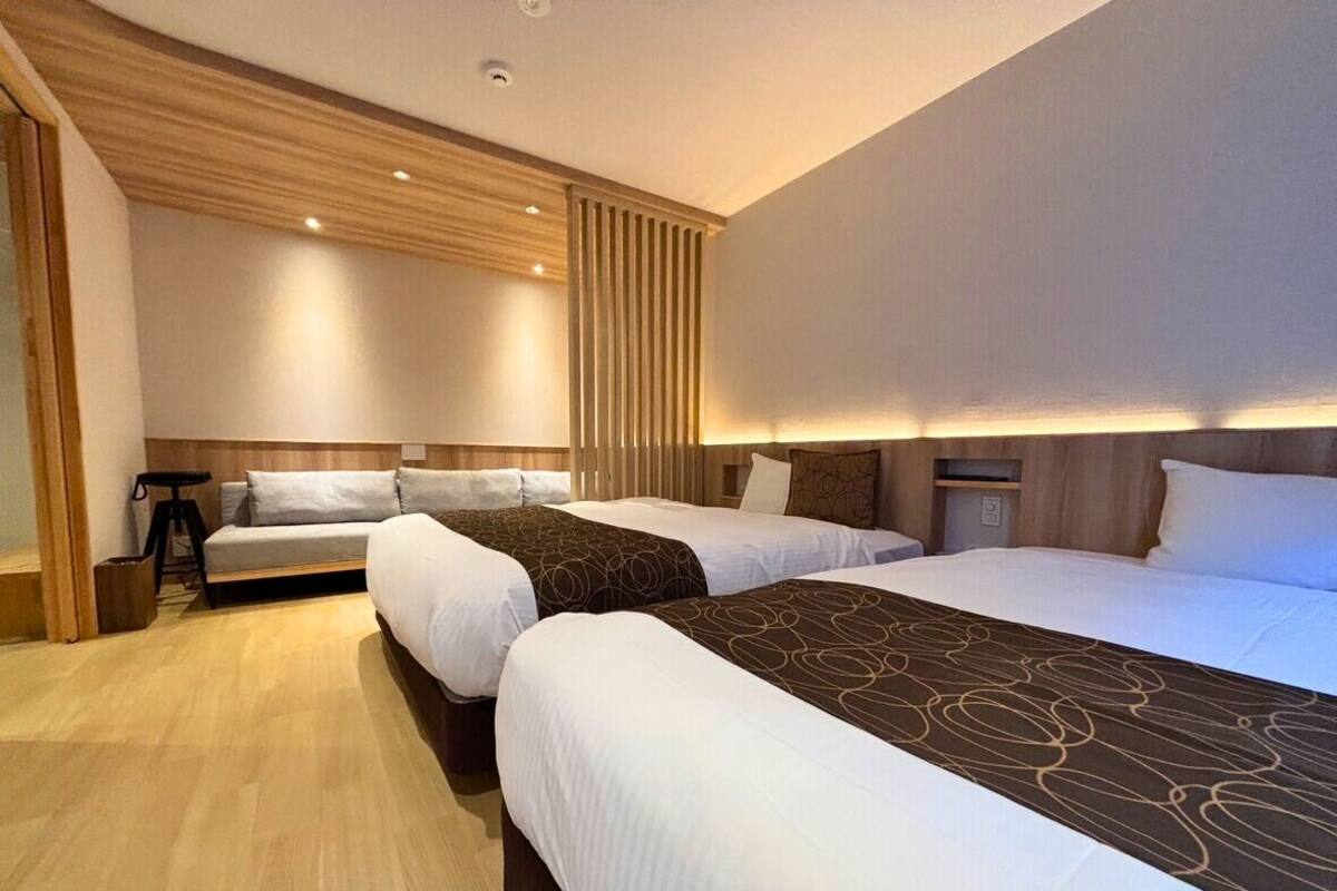 Ein Hotelzimmer mit drei Betten, Holzvertäfelung und modernem Design.