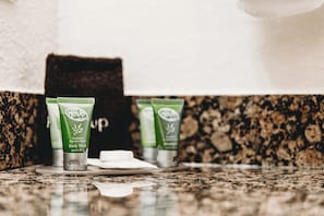 Three green tubes of body wash and shampoo on a granite countertop.