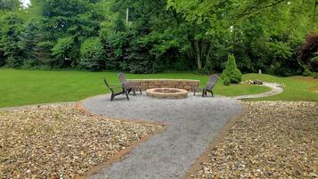A patio area with a fire pit, two Adirondack chairs, and a stone wall.