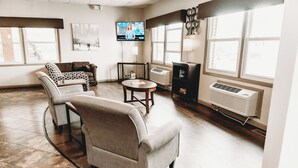 Un salon spacieux doté d’une grande fenêtre, d’un téléviseur à écran plat, d’une cheminée et d’un coin salon confortable.