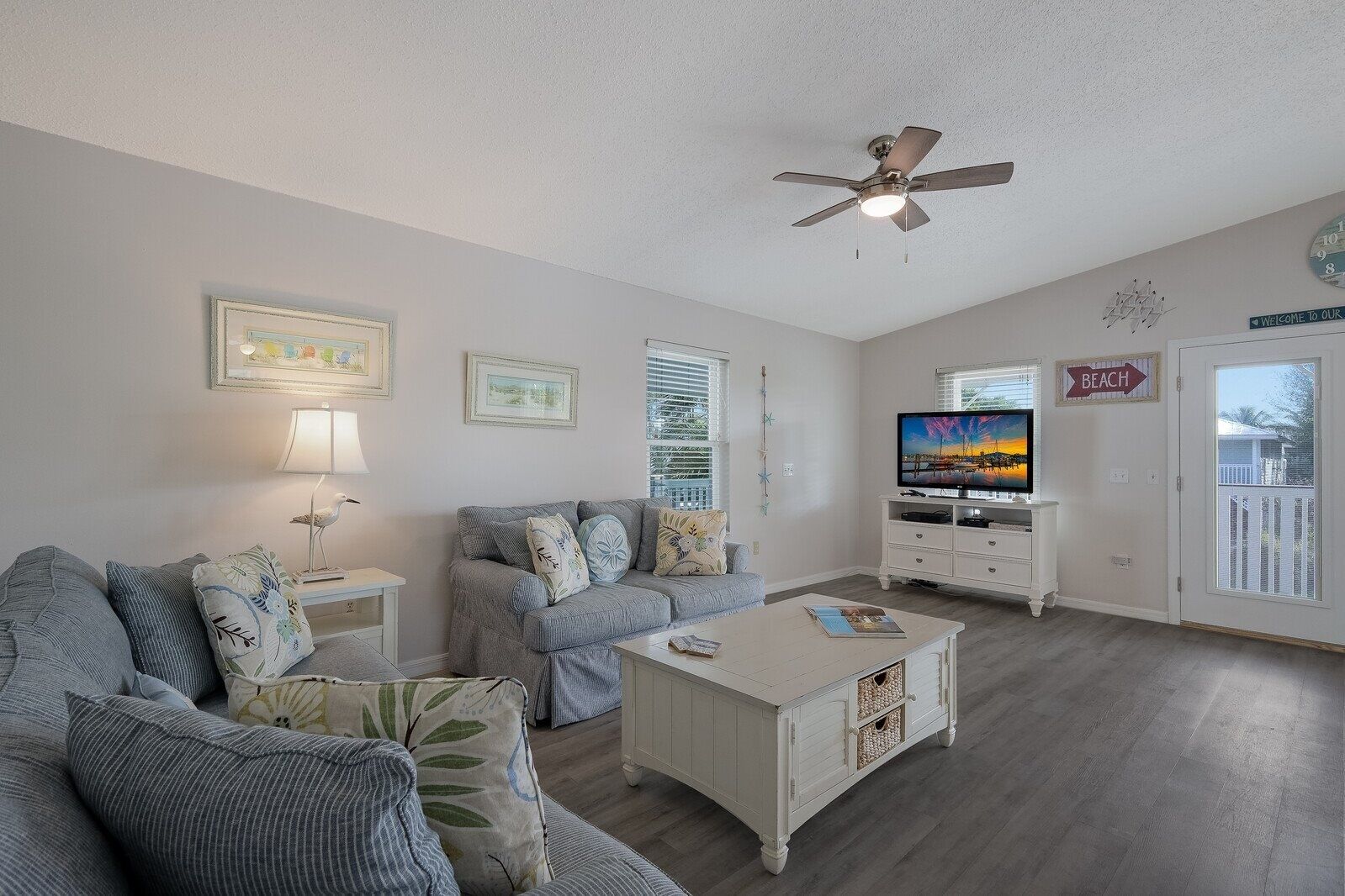 A living room with a sofa, a coffee table, a TV, and a ceiling fan.