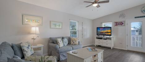 A living room with a sofa, a coffee table, a TV, and a ceiling fan.