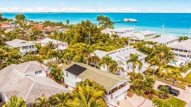 A coastal residential area with houses, palm trees, and a view of the ocean.