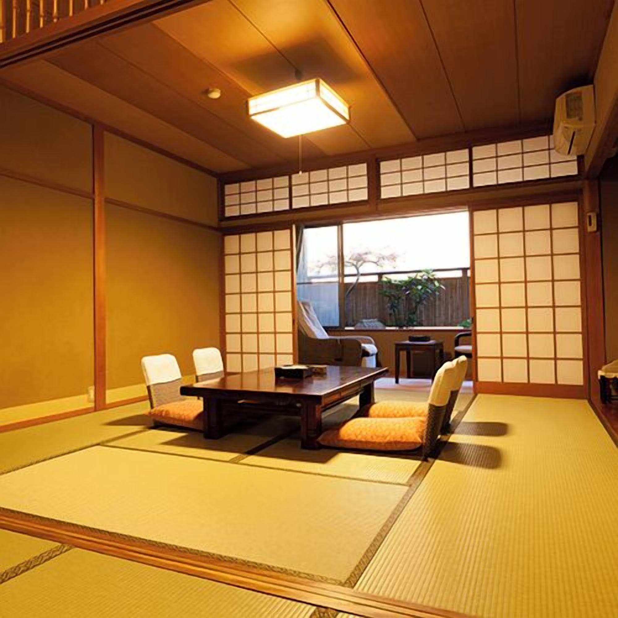 A tatami mat room with a low table and chairs, a window with a view, and a ceiling light.