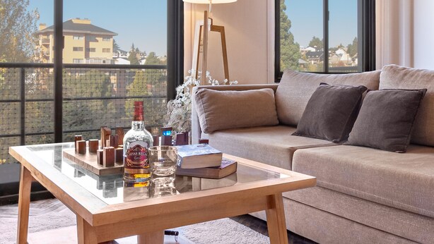 Ein modernes Wohnzimmer mit Glastisch, Sofa und Stehlampe.
