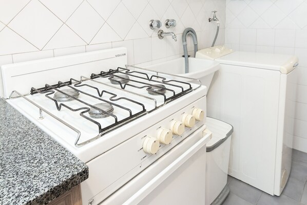 A kitchen with a white stove, sink, and oven. - DEPARTAMENTO EN EL CENTRO CON VISTA AL LAGO N.HUAPI (San Carlos de Bariloche)