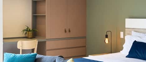 Una habitación de hotel moderna con cama, sofá, escritorio y una planta en maceta.