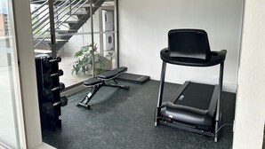 A gym with a treadmill, weights, and a stairwell.