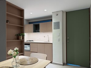 A modern kitchen with built-in appliances, a dining area with a table and chairs, and a green door.