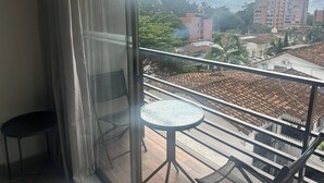 A balcony with a glass door, a small round table, and a chair.