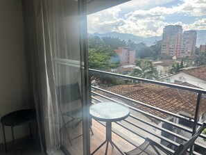 A balcony with a glass door, a small round table, and a chair.